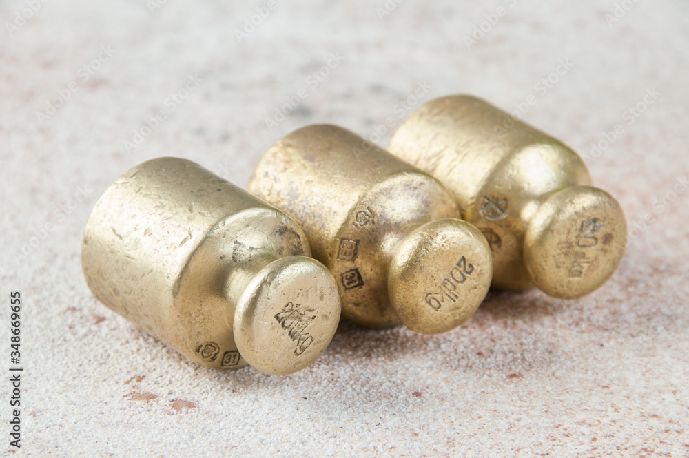 Three antique bronze weights for scales on concrete background. Three antique bronze weights for scales on concrete background.