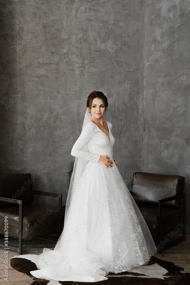 beautiful bride stands in a wedding dress on a dark background,studio portrait of a bride,bride stands on faux leather