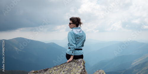 Gilr sitting on a high mountain. Freedom, traveling, hiking and trekking concept.