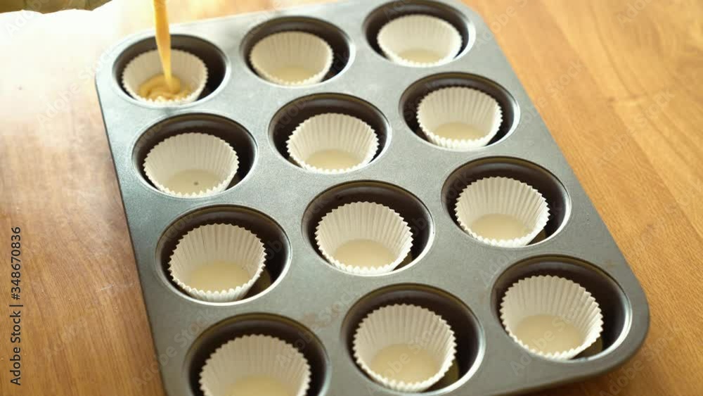 Senior housewife pouring dough in muffin cases Senior housewife pouring dough in muffin cases