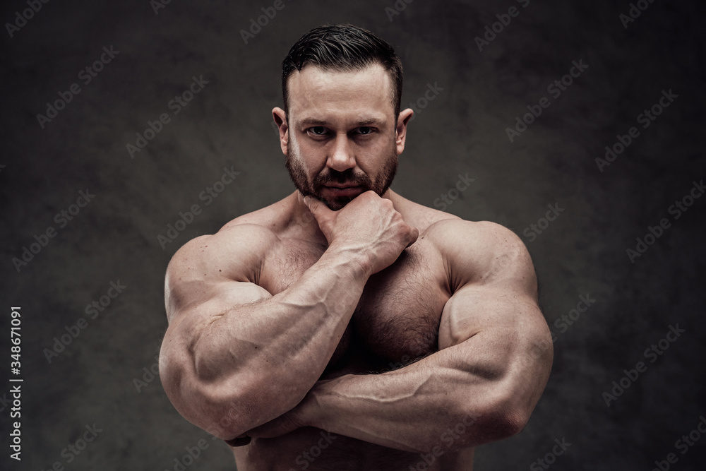 Close-up photo of a shirtless athlete looking thoughtfull in a dark studio