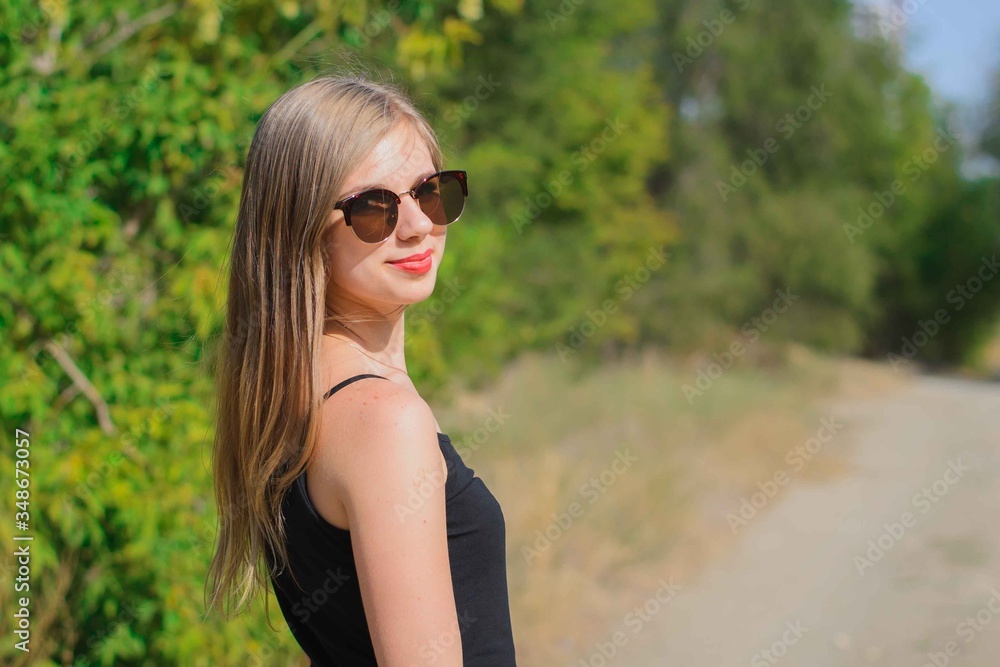 young blonde of European descent walks through the woods in a fashionable plain black blouse young blonde of European descent walks through the woods in a fashionable plain black blouse