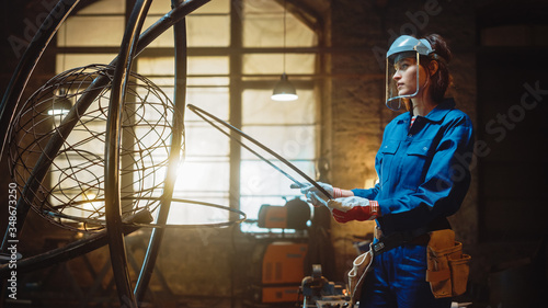 Wallpaper Mural Young Contemporary Female Artist in Blue Jumpsuit and Safety Mask is Fitting a Metal Ring to a Tube Sculpture in a Studio Workshop. Empowering Woman Makes Modern Brutal Abstract Artwork Out Of Steel. Torontodigital.ca
