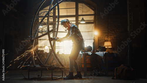 Talented Innovative Tomboy Female Artist Uses an Angle Grinder to Make an Abstract, Brutal and Expressive Metal Sculpture in a Workshop. Contemporary Fabricator Creating Modern Steel Art. photo