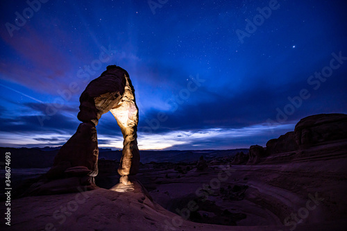 Night sky and stars behind Delicate Arch at Arches National Park after sunset.