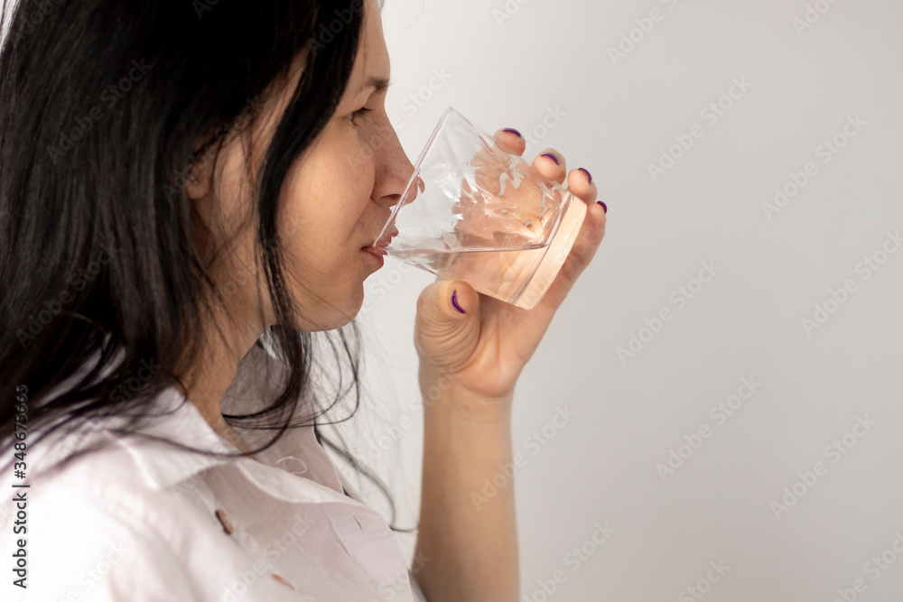 Beautiful young girl drinks water from glass Beautiful young girl drinks water from glass