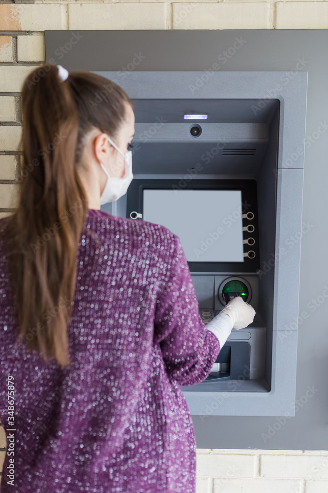 Woman with medical mask holding credit card and withdrawing cash from ATM. Covid-19 concept. Woman with medical mask holding credit card and withdrawing cash from ATM. Covid-19 concept.