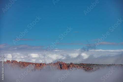 Clouds rising around Fiery Furnace at Arches National Park in snow when sun is rising.