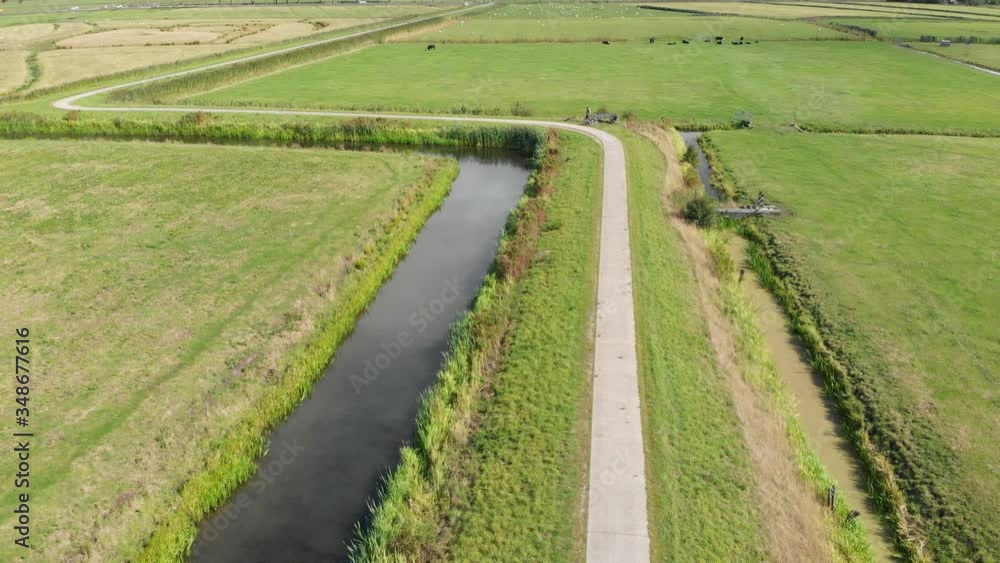 Aerial view of road cyclists. Tourists enjoying a bicycle ride riding along the polder in Netherlands. People cycling on his bicycle through Dutch polder landscape. Active sport people. Summer trave Aerial view of road cyclists. Tourists enjoying a bicycle ride riding along the polder in Netherlands. People cycling on his bicycle through Dutch polder landscape. Active sport people. Summer trave