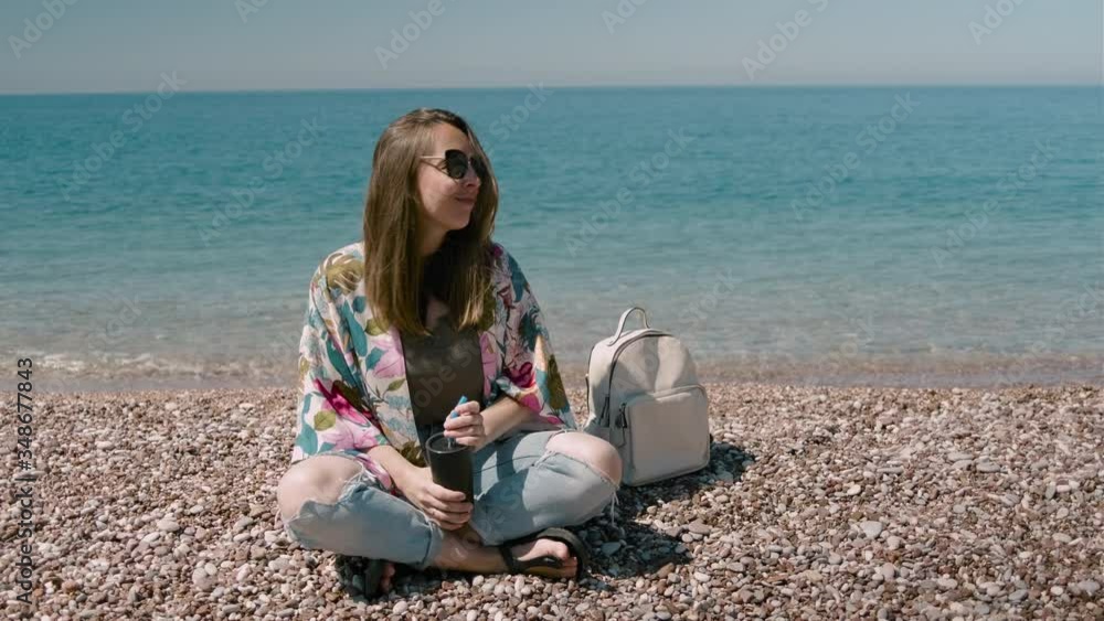Young millennial woman drinking coffee from keep cup and sitting on the ...