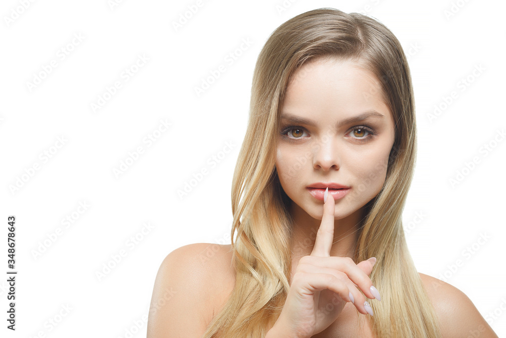 A stylish beautiful girl with loose hair looks at the camera and points her finger at the gesture of silence. A stylish beautiful girl with loose hair looks at the camera and points her finger at the gesture of silence.