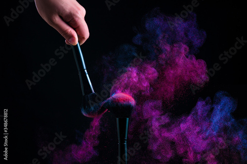 Powder blows from makeup brushes. powder explosion on a black background
