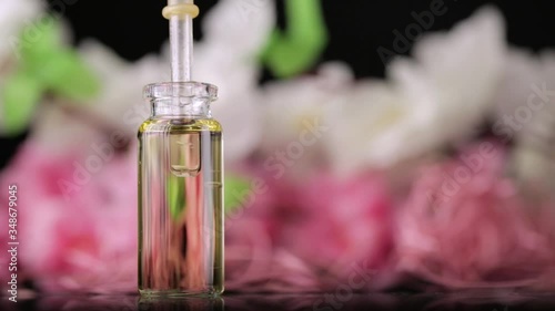 Blend of essential oils closeup. Making some aroma liquids, perfume. Drops falling from pippet to little glass bottle. Slowmotion. Liquid ingredients, body care production, cosmetology. photo