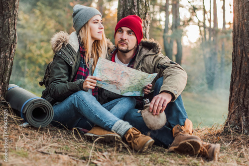 Travel couple camping with map in the forest. Concept of trekking, adventure and seasonal vacation.