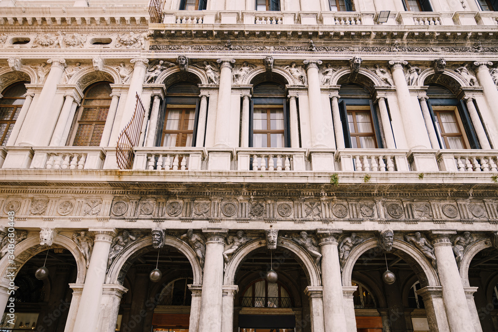 Building Fondazione Musei Civici di Venezia in Venice, Italy. Stone bas-reliefs on the facade of building in Piazza San Marco, classic Venetian windows, columns, balconies with small columns, stucco.