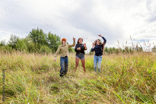 Summer holidays vacation happy people concept. Group of three friends boy and two girls dancing and having fun together outdoors. Picnic with friends on road trip in nature.
