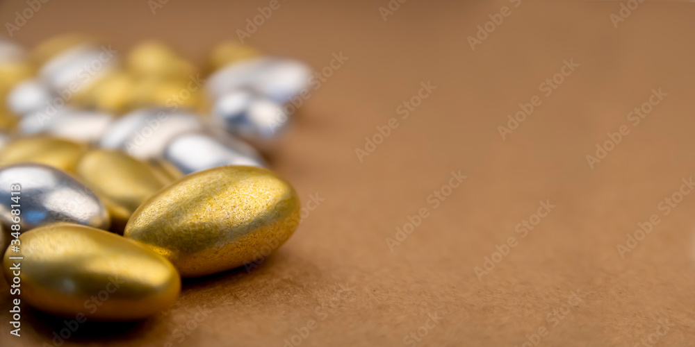 Side view and shallow depth of field of silver and gold almond candies for special events. Luxury sweet confections with textured background and copy space Side view and shallow depth of field of silver and gold almond candies for special events. Luxury sweet confections with textured background and copy space