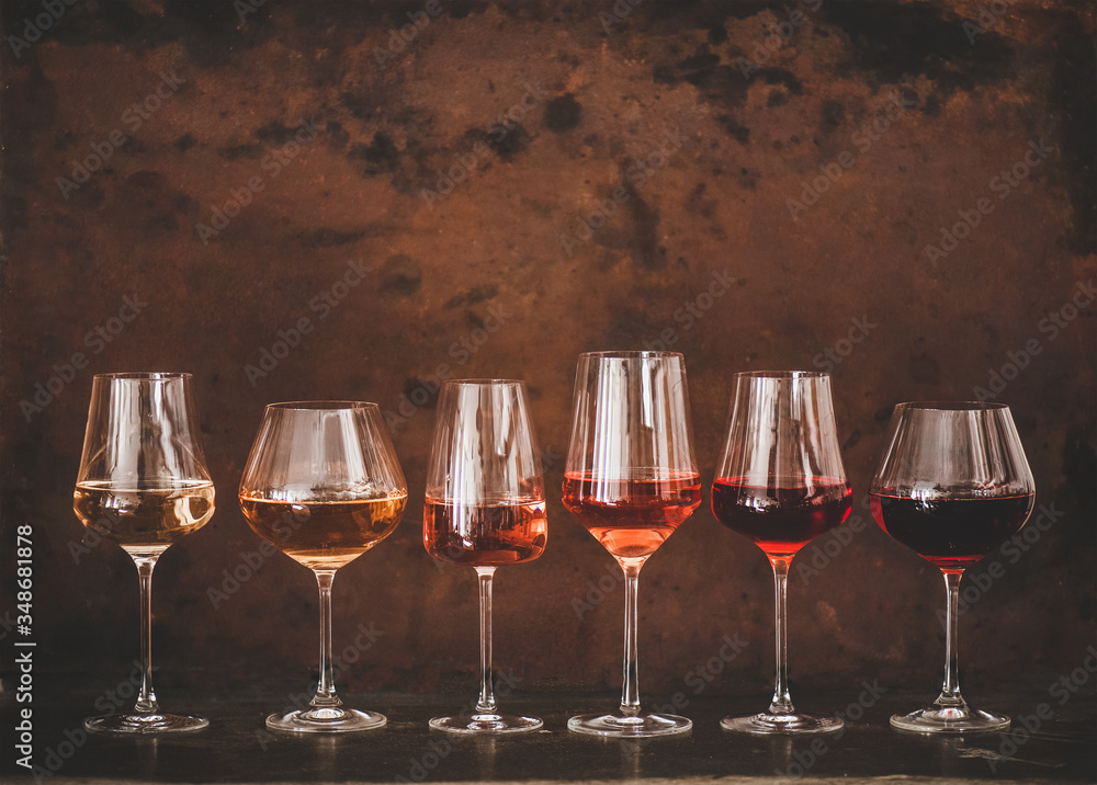 Various shades of Rose wine in stemmed glasses placed in line from light to dark colour on concrete table, rusty brown background behind, copy space. Wine bar, wine shop, wine tasting concept - obrazy, fototapety, plakaty 