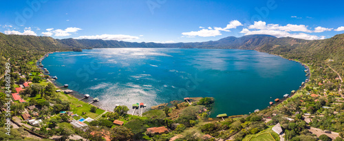 Panoramic view of the beautiful lake of Coatepeque in El Salvador, with a blue sky, in the season where its waters are turquoise and most of its mountains and vegetation are green. photo