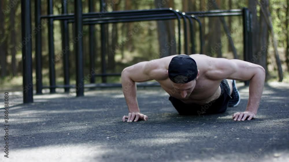 Adult caucasian athlete is doing push ups topless at the gym at the park on his daily workout Adult caucasian athlete is doing push ups topless at the gym at the park on his daily workout