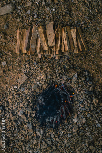 Leftovers of a small bonfire made by children with small logs and pricks as a part of a game. Black charcoal on a mini bonfire viewed from above. photo