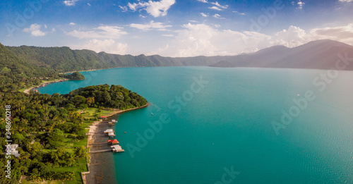 Fototapeta Naklejka Na Ścianę i Meble -  Aerial view of the coatepeque lake in El Salvador, where you can see the mountains that surround the lake, a sky almost clear only with some clouds, in the season where its waters turn turquoise.