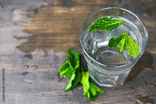 Pure cold water with mint petals on a wooden background. Detox theme. Selective focus.