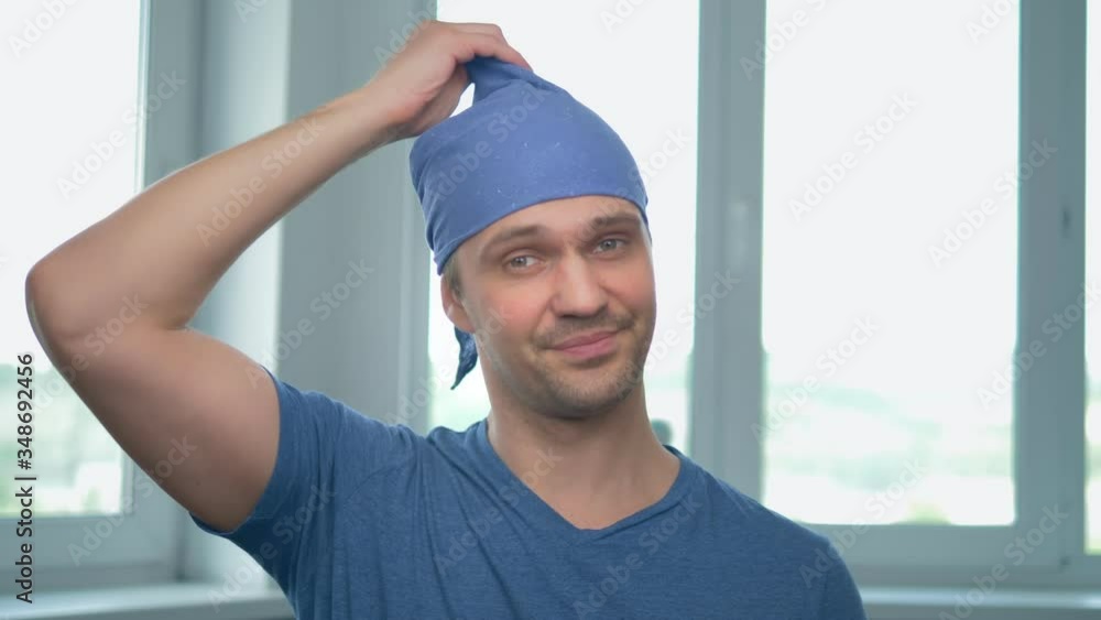 handsome man removes the bandana, his bald head becomes visible handsome man removes the bandana, his bald head becomes visible