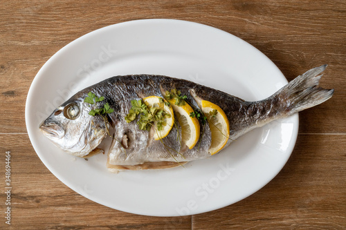 Obraz na płótnie Dorada fish fried with lemon and parsley on a white plate w salonie