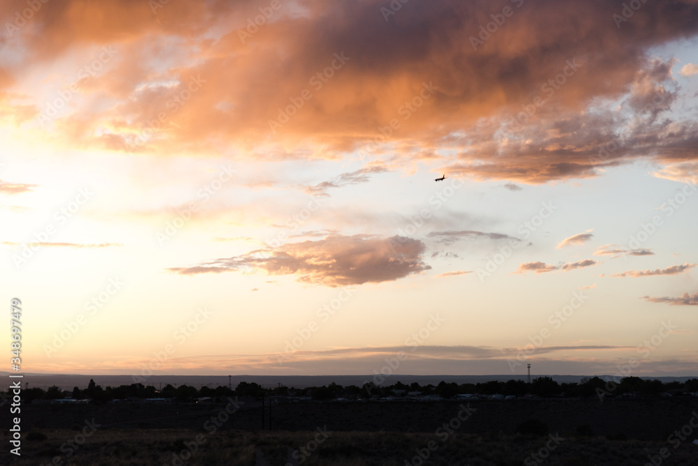 An airplane flying close to the ground during a sunset. 