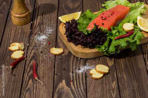 red fish fillet on a wooden background. trout, lettuce, crackers, toasts, red pepper. preparing breakfast