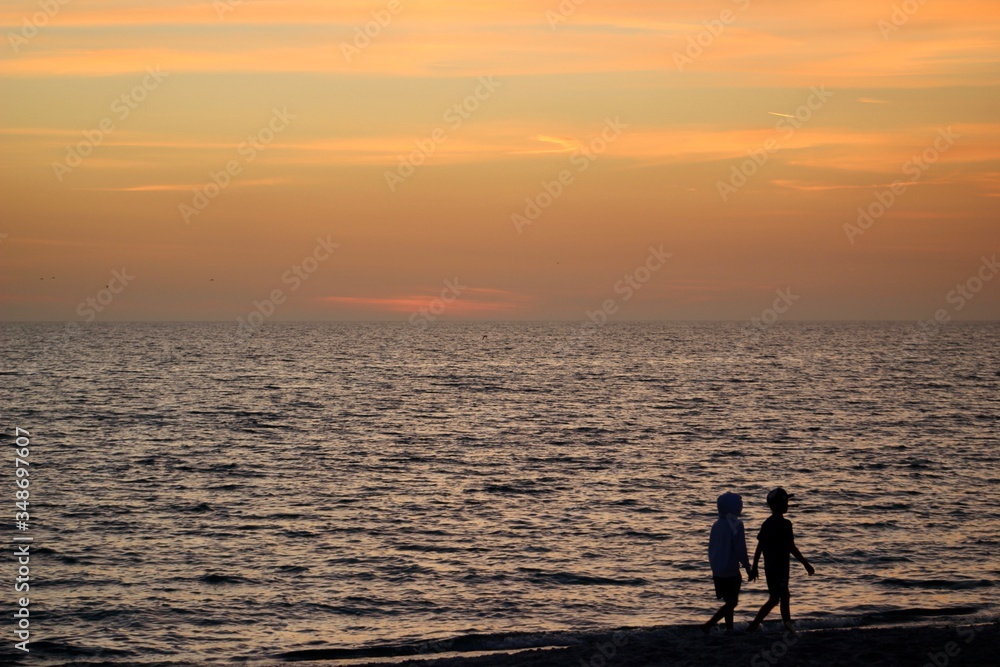 Silhouette of a two children walking on the beach at sunset
