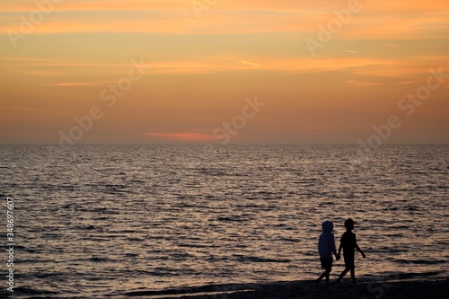 Silhouette of a two children walking on the beach at sunset