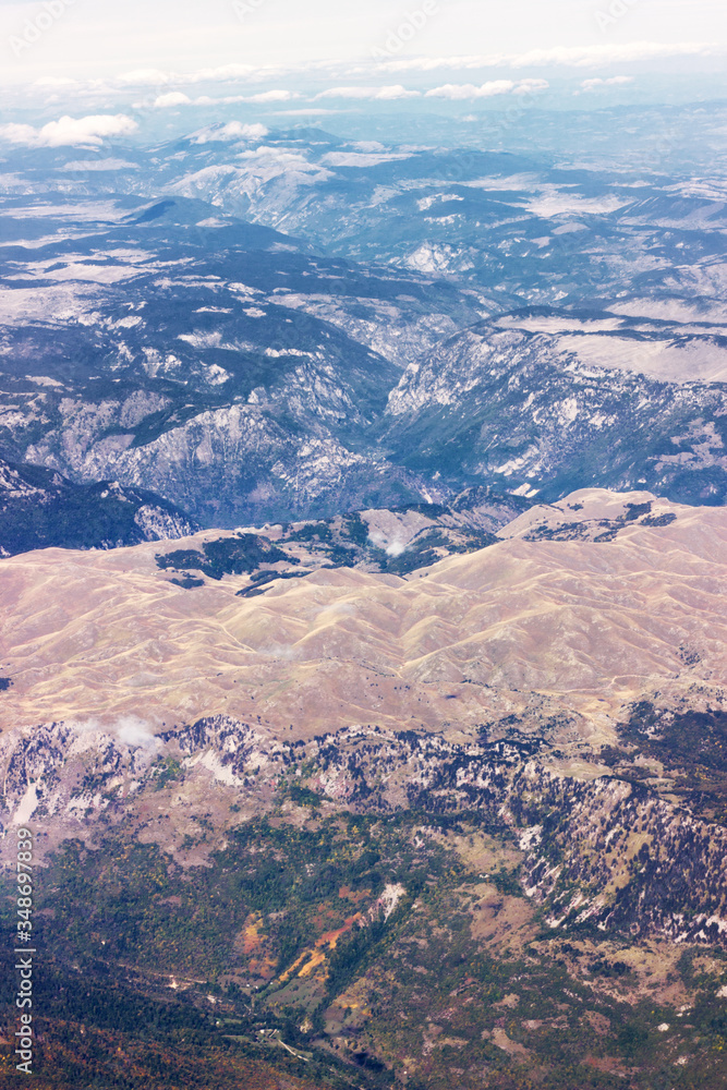 Beautiful mountain landscape  background. Group of mountains view from the great height airplane porthole. High altitude мassif. Vertical image