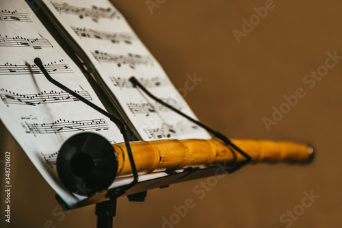closeup scene of an oriental musical instrument Ney, stays on the music sheet stand with notes, isolated, mystic scene, traditional eastern and turkish folk music materials