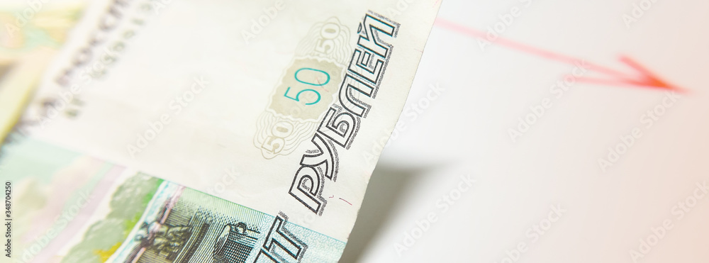 Russian currency and regressive chart. A bill of fifty Russian rubles and a red graph with an arrow. The concept of the Fall in the price of the Russian ruble, falling oil prices. Russian currency and regressive chart. A bill of fifty Russian rubles and a red graph with an arrow. The concept of the Fall in the price of the Russian ruble, falling oil prices.
