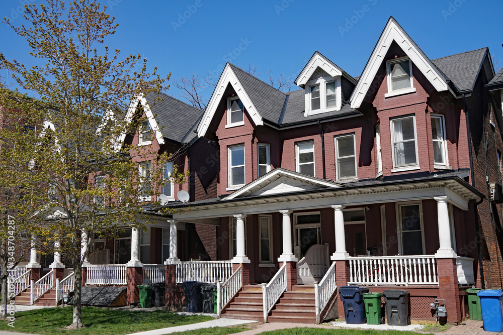Street with row of identical old painted brick houses with pointed gables Street with row of identical old painted brick houses with pointed gables