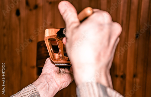 closeup scene of polishing wooden musical instrument with brush, in workshop, highlighted perspective with opposite angle photo