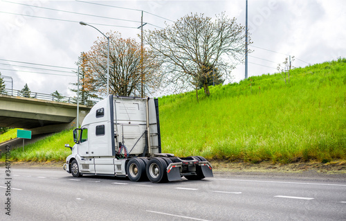 Big rig diesel semi truck tractor running on the highway road to warehouse for pick up loaded semi trailer photo