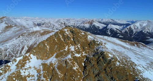 Aerial panning shot of snow covered rocky mountain against sky, people on idyllic landscape during winter - Falkert, Austria photo