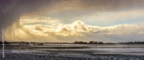 Snowy meadow field with cloudy sky in sunrise