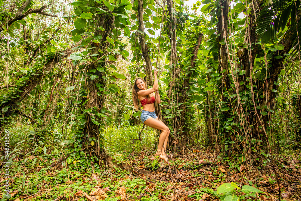 A young girl having fun while swinging from reeds in a tropical forest. A young girl having fun while swinging from reeds in a tropical forest.