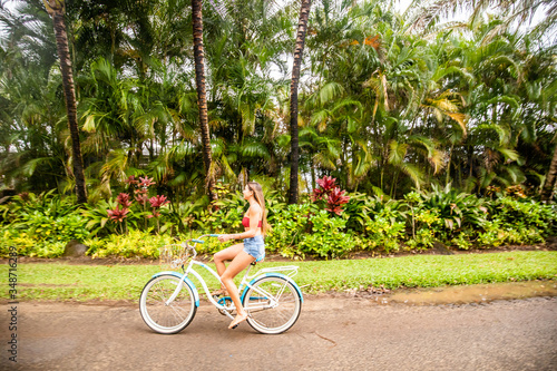 A young girl riding her bicycle on a rural road in a tropical area of Kauai in Hawaii. 