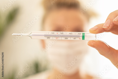 Woman measures the body temperature at home.