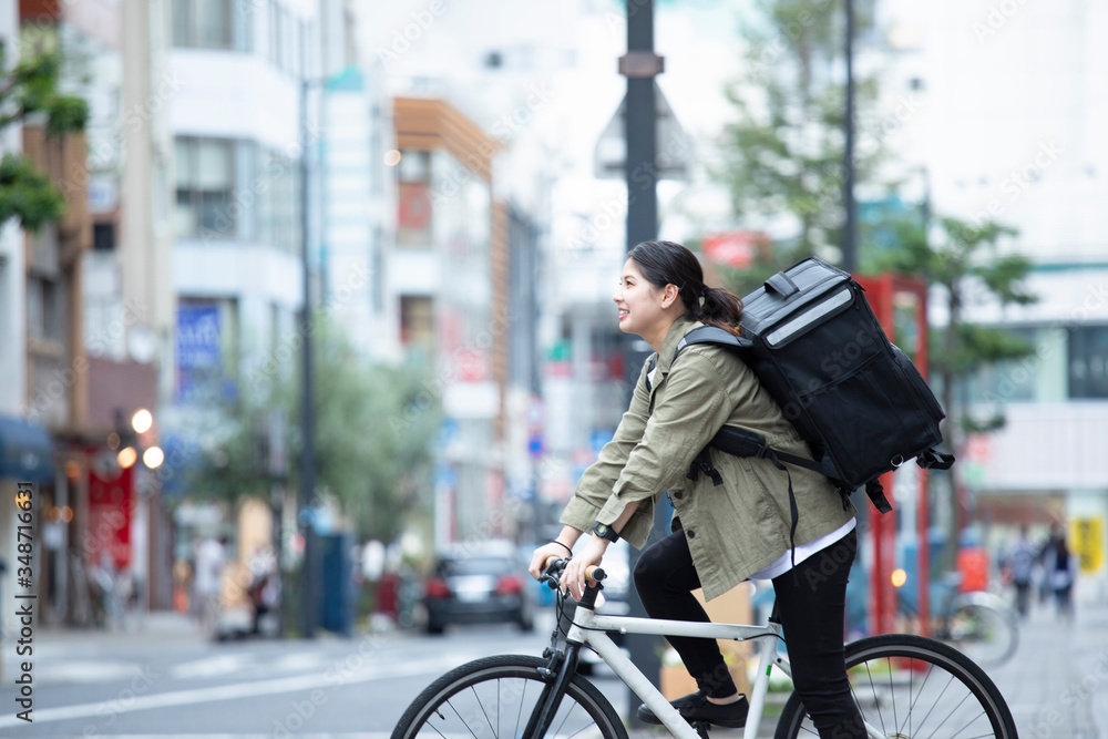 Fototapeta premium 自転車で荷物の配送を行う若い女性