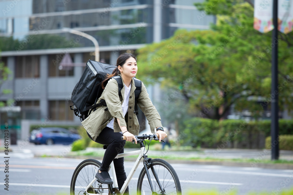 自転車で荷物の配送を行う若い女性
