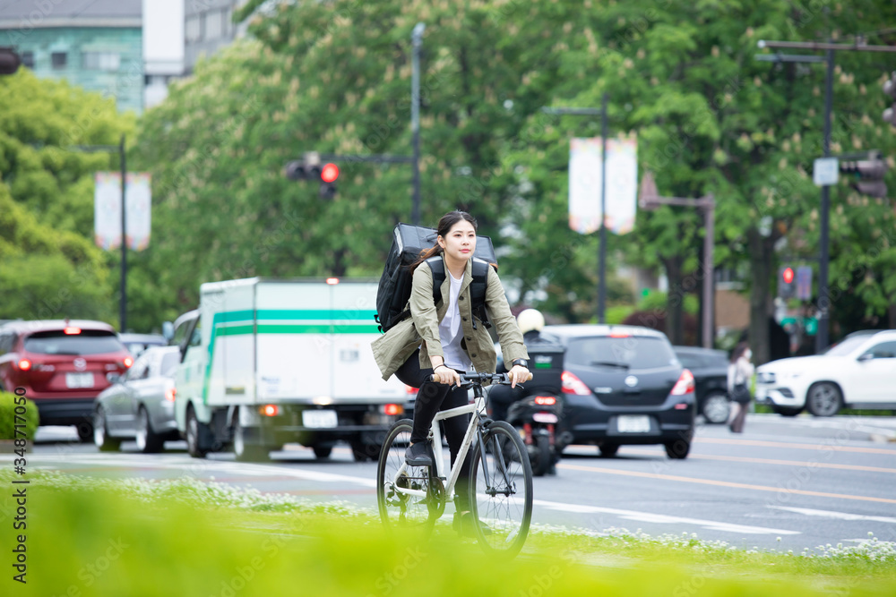 自転車で荷物の配送を行う若い女性
