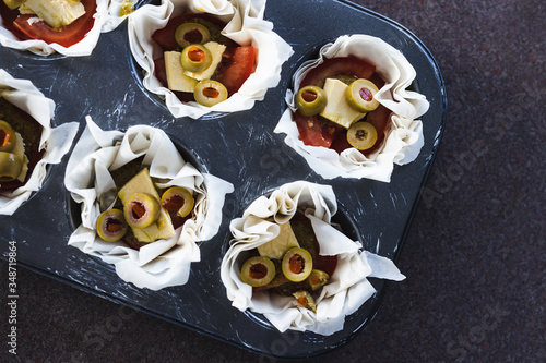 plant-based food, filo pastry cups with vegan filling made of tomatoes olives pesto and dairy-free cheese photo