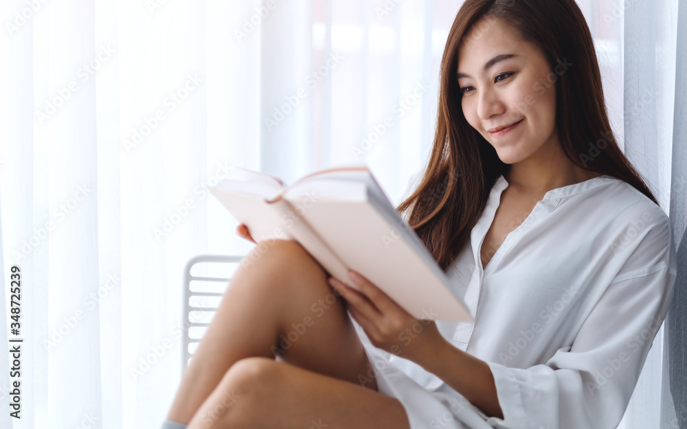 Closeup image of a beautiful asian woman reading book in a bedroom at home Closeup image of a beautiful asian woman reading book in a bedroom at home
