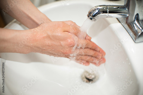 man use soap and washing hands under the water tap. Hygiene concept hand detail